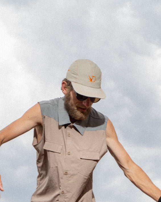 Man in outdoor attire climbing rocky terrain with mountains in the background